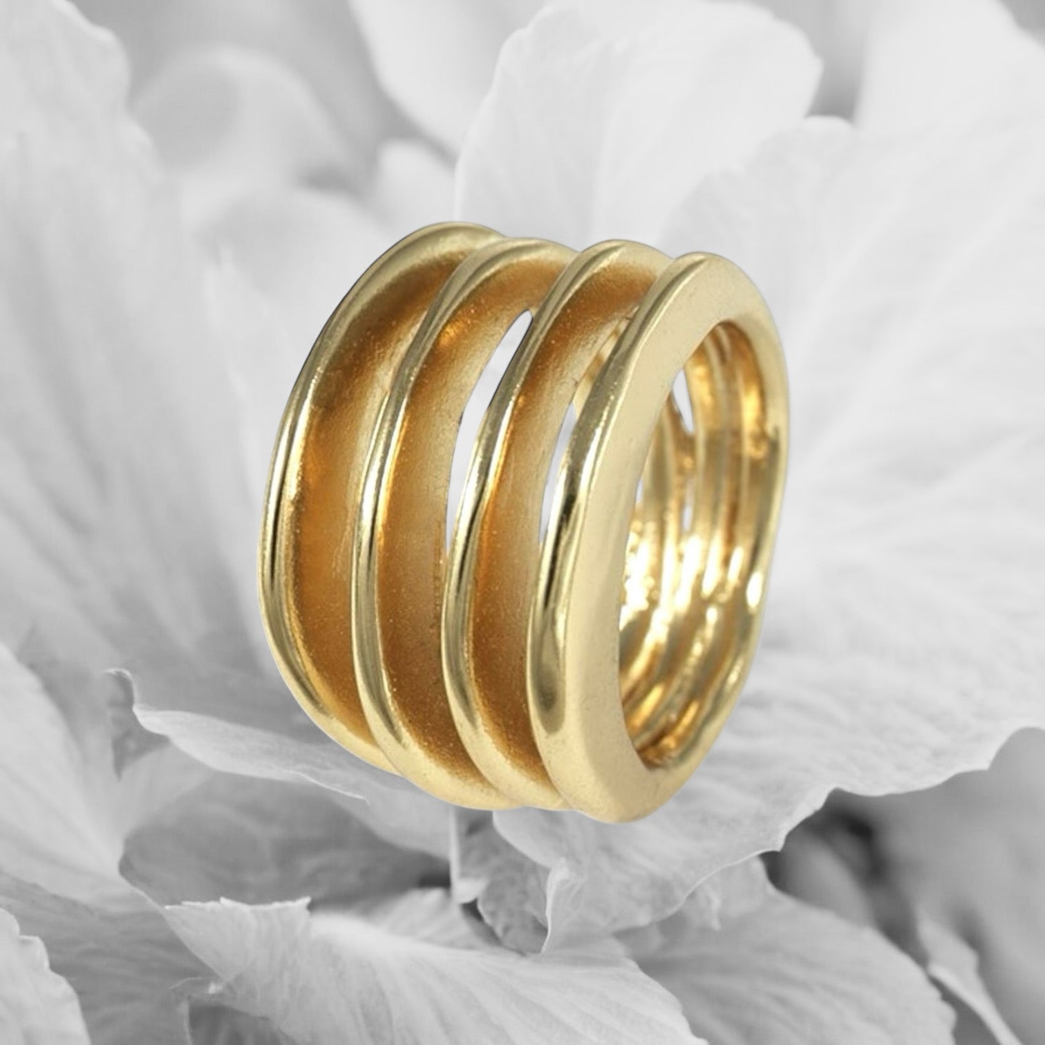 Anillo en oro AC4G de la colección Candela sobre un fondo con flores blancas