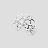 Pulsera en plata BC2S de la colección Candela sobre fondo de color