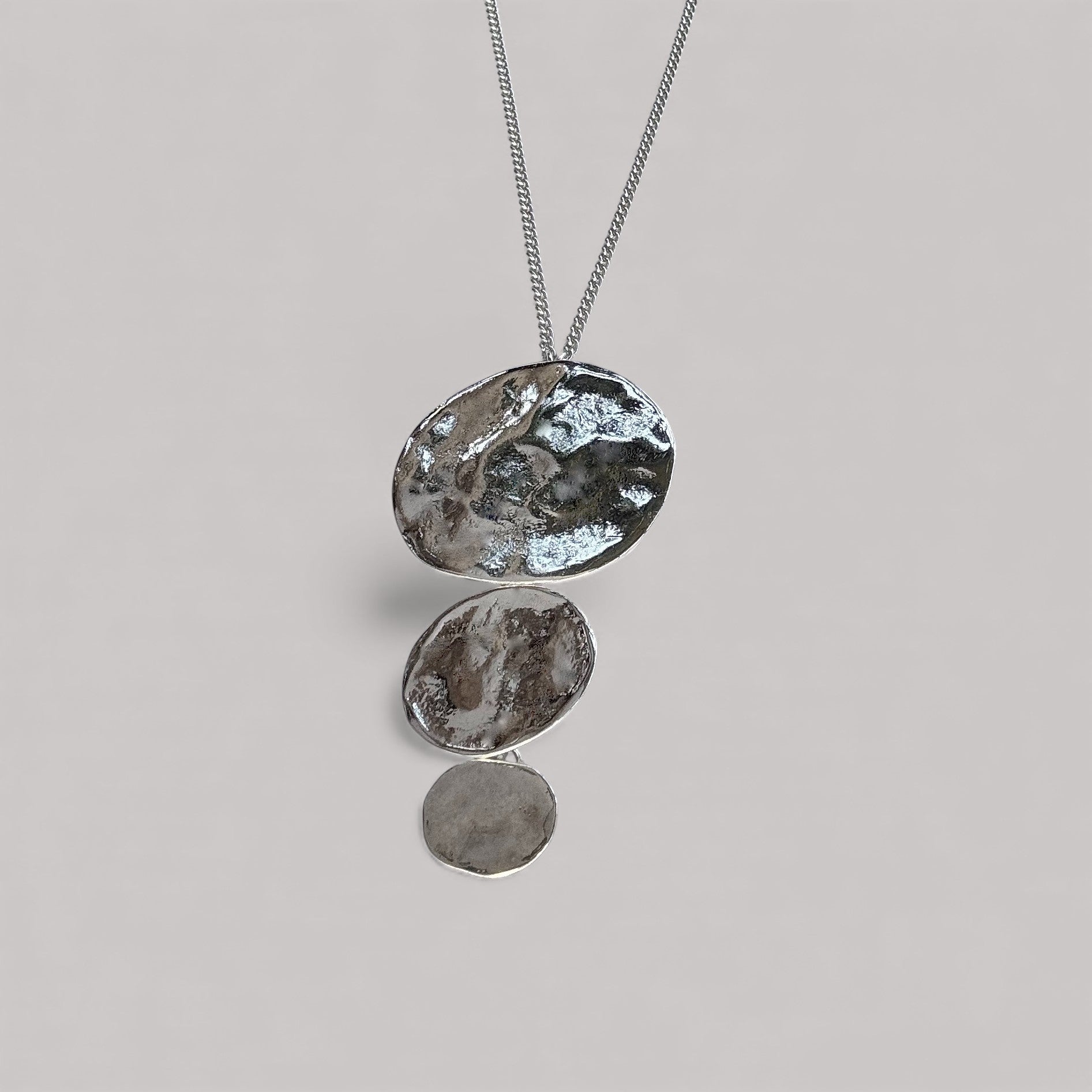 Colgante en plata CA2S de la colección ABRIL sobre un fondo de color