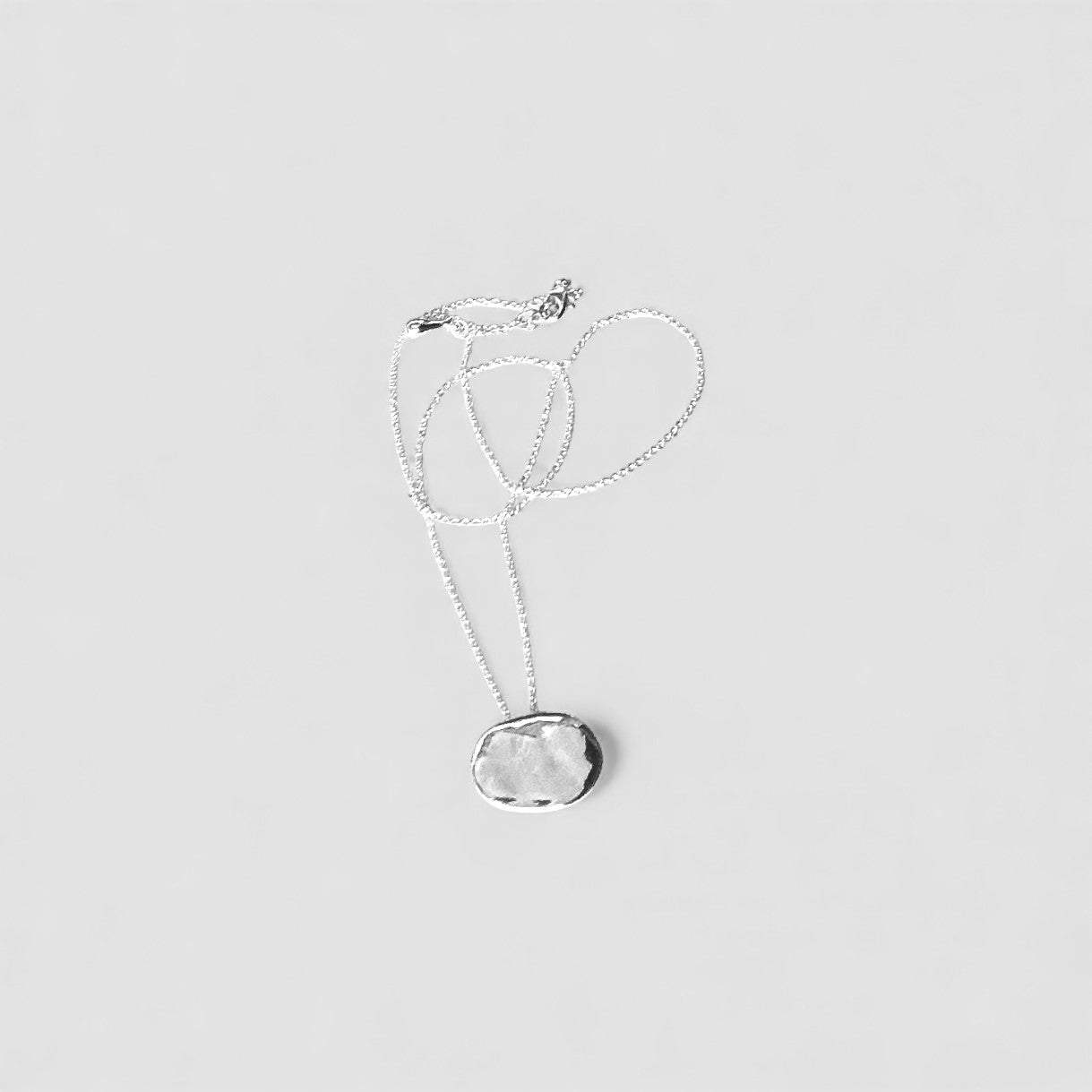 Colgante en plata CA8 de la colección Abril
sobre fondo de color