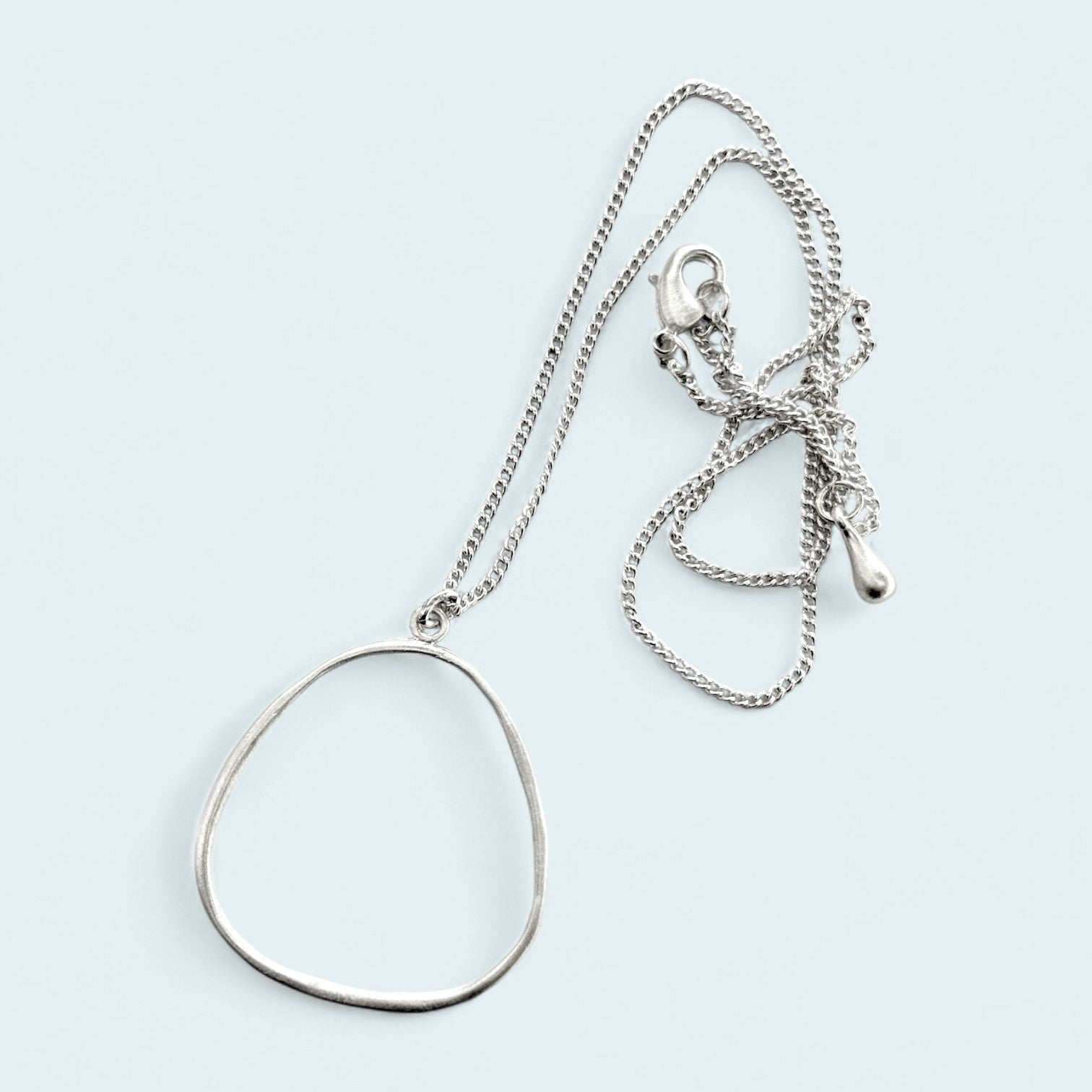 Collar en plata CC1G de la colección Candela sobre fondo de color