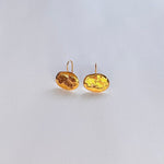 Pendientes en oro PA2 de la colección Candela sobre fondo de color