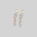 Pendientes en oro mate PB1 de la colección Brisa sobre un fondo de color