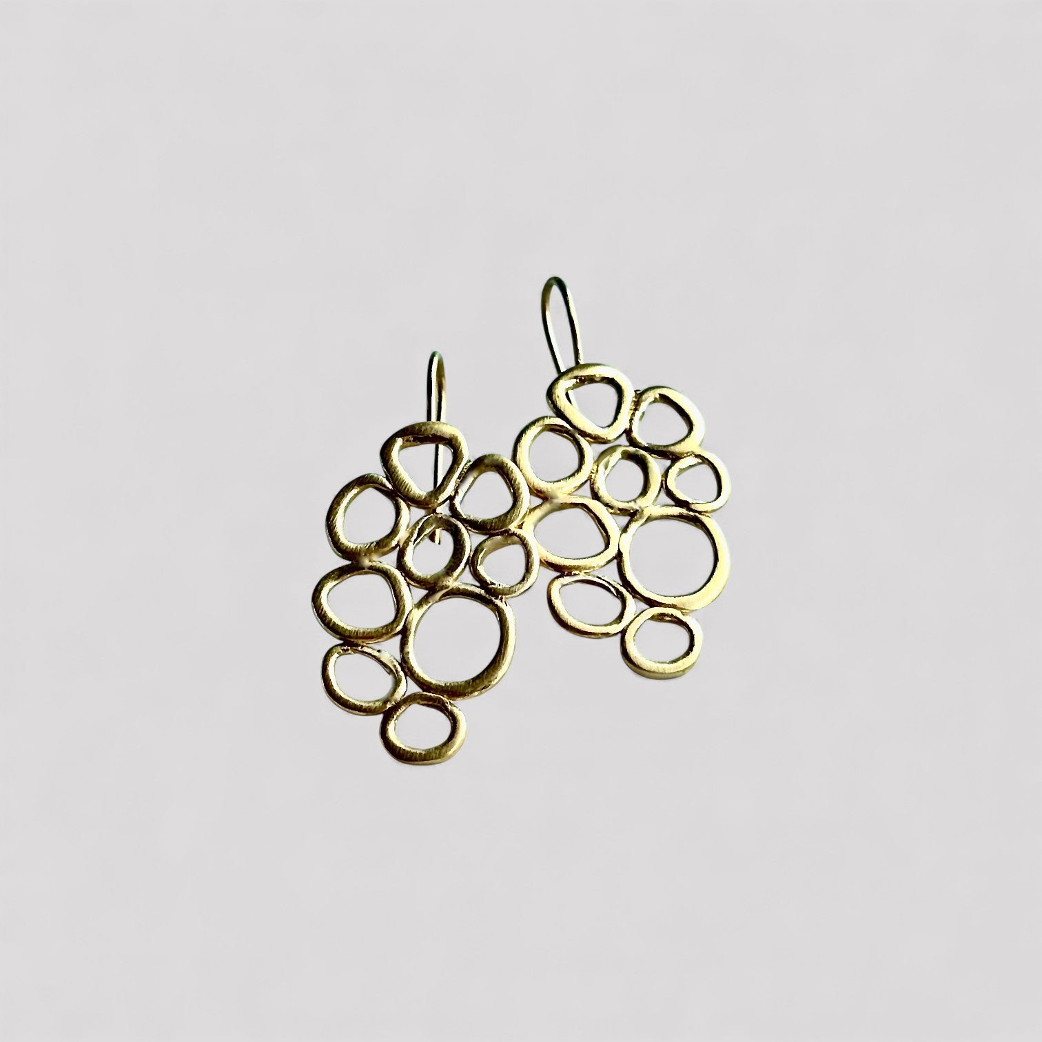 Pendientes en oro mate PB3GH de la colección Brisa sobre un fondo liso con sombra