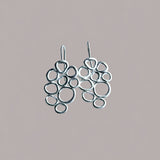 Pendientes en oro mate PB3GH de la colección Brisa sobre un fondo liso con sombra