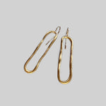 Pendientes en oro PC1 de la colección Candela sobre fondo de color