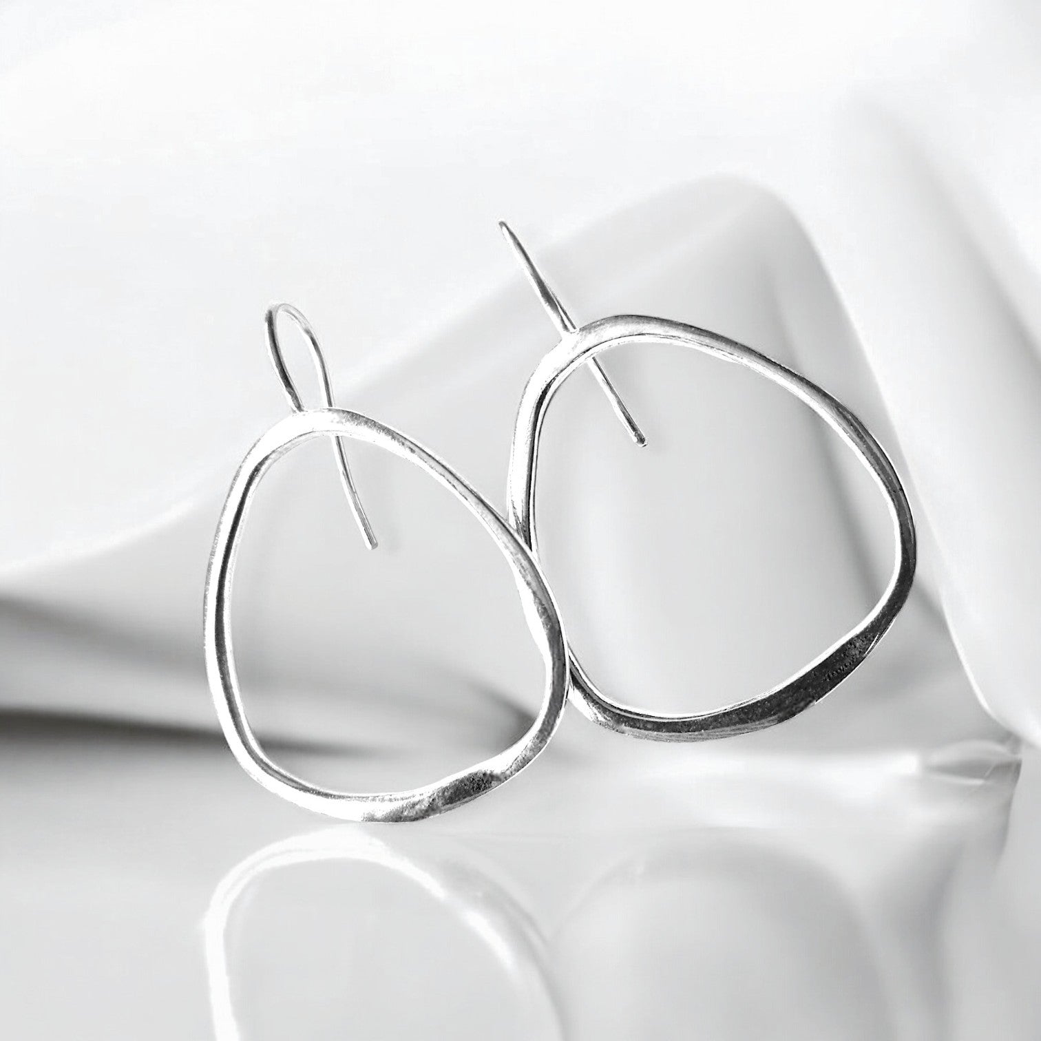 Pendientes en plata PC5 de la colección Candela sobre un fondo liso con sombra