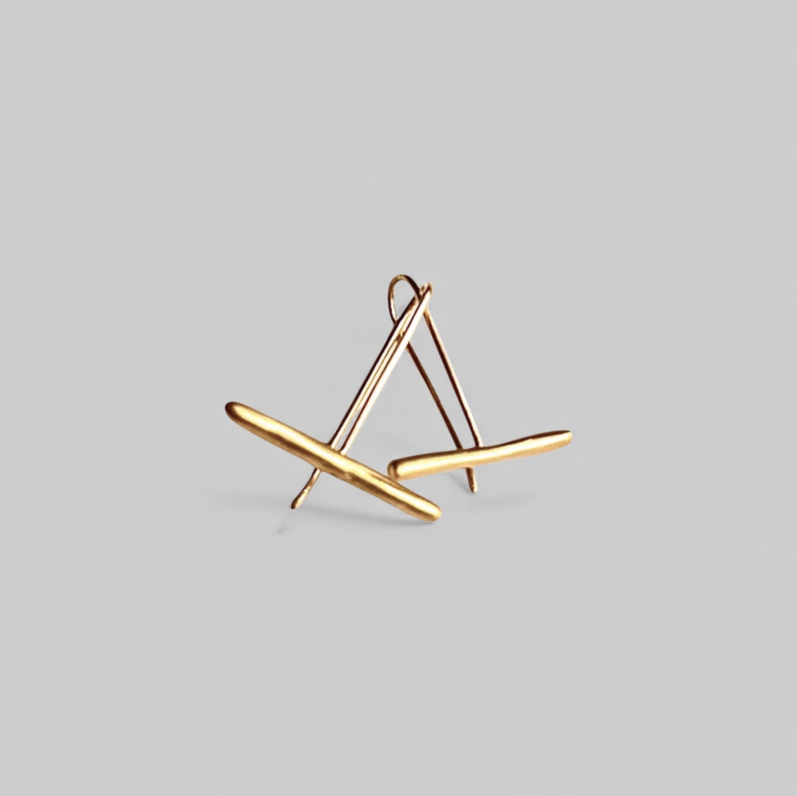 Pendientes en oro PC9 de la colección Candela con cierre de gancho sobre un fondo de color