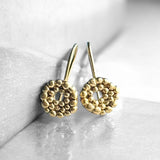 Pendientes en oro mate PB4SS de la colección Brisa sobre fondo liso con reflejo
